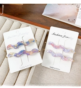 Detail of wavy acetate hair clips with marble texture in soft macaron gradient colors
