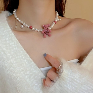 Close-up of cute pink flocked bear pendant on a white faux pearl necklace with rhinestones