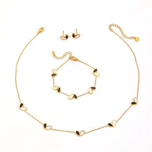 Three-piece gold jewelry set featuring black and white heart charms on necklace and earrings