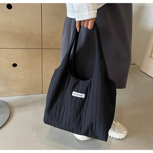 Detail einer schwarzen Stofftasche mit Plisseestruktur und gewebtem Kiss Yourself Etikett