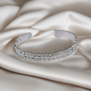 Macro detail of silver feather texture engraving on luxury stainless steel bangle