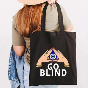 Graffiti Greek Evil Eye black canvas tote bag worn by a model in a lifestyle setting