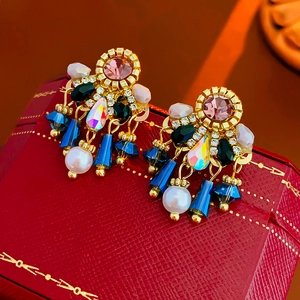 Detail of vintage-style pearl drop earrings with colorful rhinestones on a red box