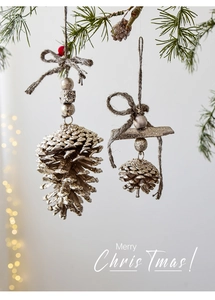 Close-up of pine cone ornaments with gold and silver glitter hanging on a Christmas tree