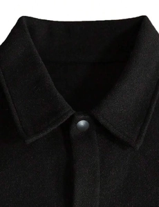 Close-up of black wool jacket lapel with matte button and soft textured fabric detail