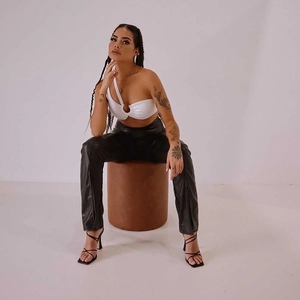 Détail d'un crop top blanc asymétrique avec anneau métallique et pantalon en cuir noir