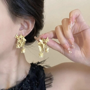 Close-up of golden butterfly earrings worn by a model to show intricate 3D metal details
