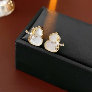 Macro shot of gold gourd earrings with pearl bow and zircons on a jewelry box