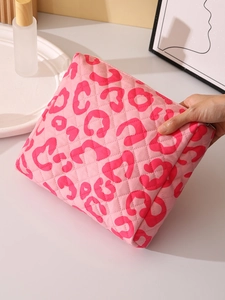 Handheld view of pink leopard print makeup bag with quilted texture and zipper