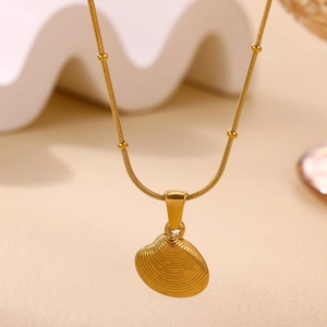 Macro shot of gold shell pendant with textured ridges on a beaded snake chain necklace