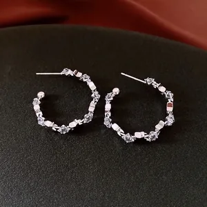 Silver-tone C-shape hoop earrings with sparkling cubic zirconia on a luxury dark background