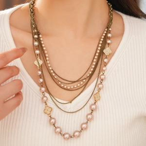 Multi-layer vintage necklace featuring champagne pearls and golden clover charms on a model