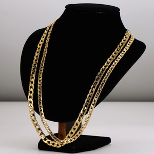 Gold-tone layered Cuban link chain necklace displayed on a black velvet mannequin bust