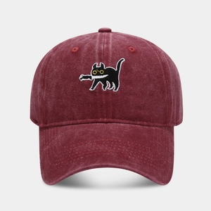 Détail de la broderie de chat noir sur une casquette en coton bordeaux délavé