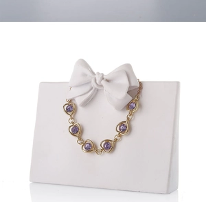 Detail macro view of a gold necklace with purple heart gemstone on a white resin display
