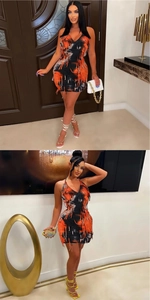Close-up of the orange and black printed mini dress featuring tassel trim and halter V-neck