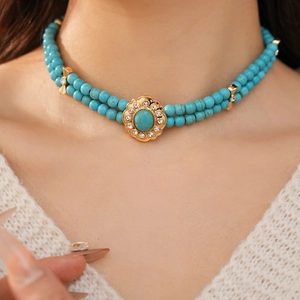 Gros plan d'un collier turquoise double couche avec pendentif fleur dorée sur modèle