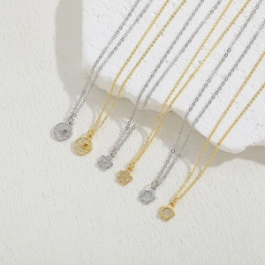 Close-up of gold and silver flower pendant necklaces with sparkling zircons on stone