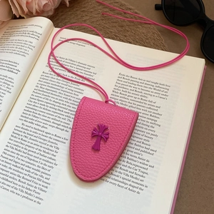 Close-up of pink leather glasses holder necklace with purple cross detail on an open book
