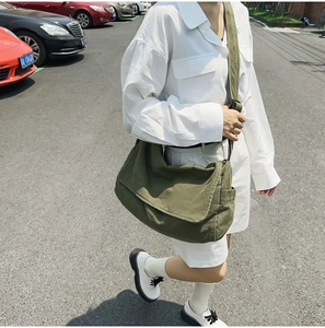 Detail of army green canvas crossbody bag with adjustable strap shown on model