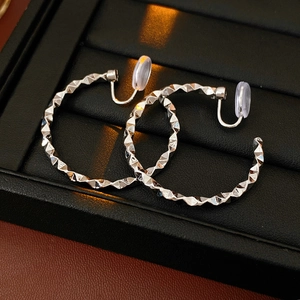 Macro detail of silver geometric rhombus clip-on earrings with soft silicone pads