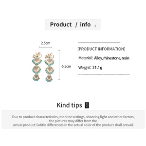 Detailed view of fan-shaped resin earrings with rhinestones and light blue tassels