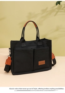 Close-up of black canvas tote bag featuring brown leather pockets and durable shoulder strap