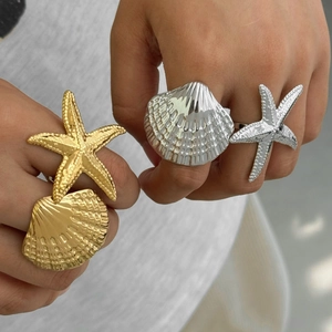 Detailed view of layered starfish and seashell rings in gold and silver stainless steel