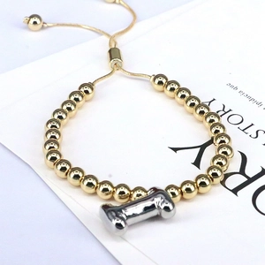 Detail of adjustable gold beaded bracelet with a silver bone charm on a display card