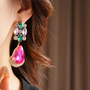 Close-up of vintage gold drop earrings with colorful crystals and a large pink pear stone