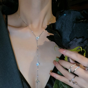 Detail of silver Y-shaped drop necklace with zircon stones on a model holding a black rose