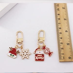 Christmas metal keychains with Santa Claus and candy charms next to a ruler for scale