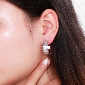 Gros plan sur les boucles d'oreilles C en acier inoxydable argenté au design dentelé
