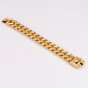 Detailed macro view of the gold-plated skull clasp on the heavy Cuban link bracelet