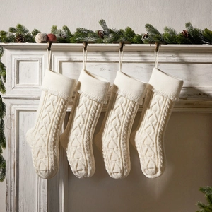 Set of 4 cream white cable knit Christmas stockings hanging on a vintage fireplace