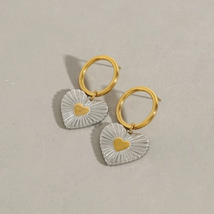 Close-up of heart-shaped drop earrings featuring gold and silver tones with radial texture