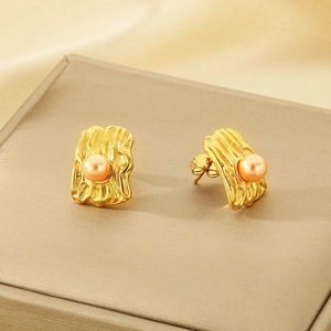 Modern irregular gold square stud earrings with champagne pearls on silk display