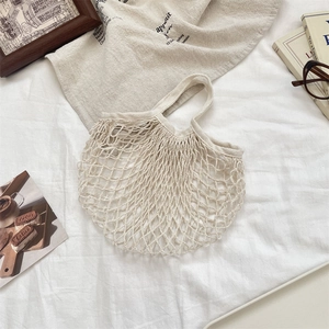 Detail of cream woven cotton mesh bag showing intricate diamond hollow pattern and texture