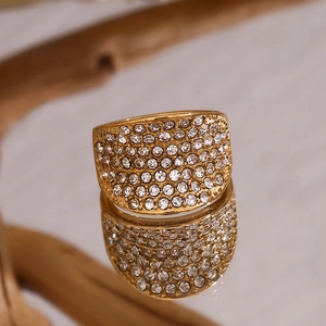 Vue macro d'une bague large dorée sertie de cristaux brillants sur support miroir