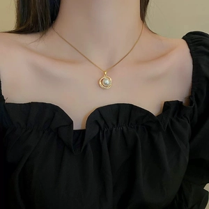 Close-up of gold stainless steel necklace with pearl pendant on model's collarbone