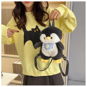 Cute penguin plush backpack with blue plaid bib worn by model in a bright indoor setting
