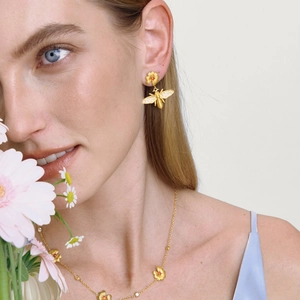 Parure en acier doré 18K avec motifs abeille et fleur orange portée par un mannequin