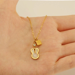 Detail of gold rabbit necklace with mother of pearl inlay and small luck charm on palm