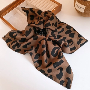 Dettaglio dell'elegante molletta per capelli con sciarpa leopardata su portagioie in legno