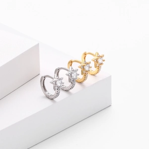 Detail of silver and gold star huggie hoop earrings with sparkling zircon inlay