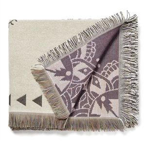 Close-up of woven camping blanket with colorful tassels and geometric jacquard texture