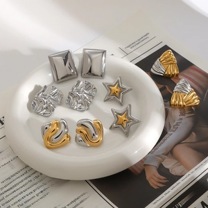 Mix of gold and silver stainless steel star earrings and textured studs on white plate