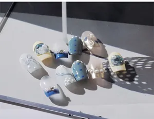 Macro detail of French style embossed nail stickers with blue gradients and pearl accents