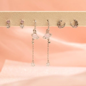 Detailed shot of celestial earrings set with pink zircon stars and moon on silk
