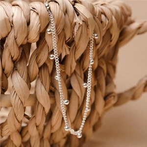 S925 sterling silver beaded anklet chain elegantly draped on a woven straw basket